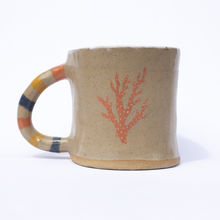 Load image into Gallery viewer, The back of a handmade ceramic mug with a striped handle and an illustration of coral.