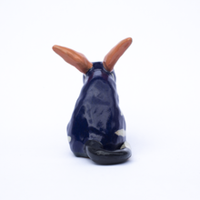 Load image into Gallery viewer, Back view of a handmade ceramic sculpture of a dark blue and white bilby with pink ears and black tail..
