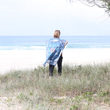 Load image into Gallery viewer, A woman walking along a grassy section at the beach. She has a scarf in a blue colour with sea creatures draped over her shoulders like a cape. The woman faces towards the sand and waves.