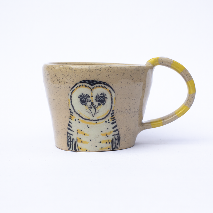 Handmade ceramic mug with a yellow striped handle and an illustration of a masked owl.