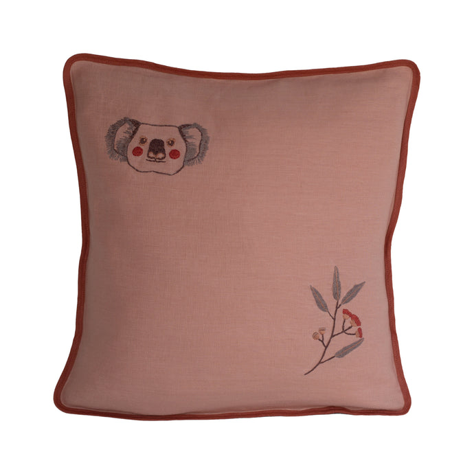 Vintage blush pink linen cushion with a darker vintage pink binding. Embroidered koala face in the top left corner with rosy pink cheeks, and embroidered gum leaves and pink flowering gum in the bottom right hand corner.