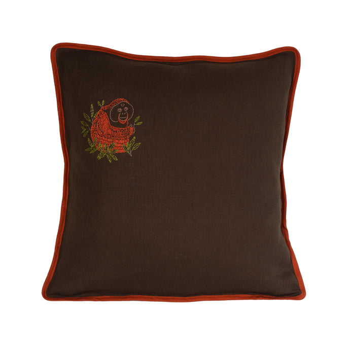 Hand embroidered orangutan with leaves surrounding him, on a dark olive linen cushion with burnt orange binding. 