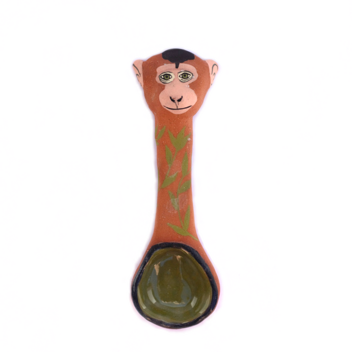 Ceramic spoon with a sculptered monkey head at the top and leaves painted on the spoon body.