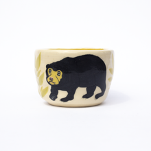 Load image into Gallery viewer, Handmade  ceramic cup with an illustration  of a sun bear and some leaves.
